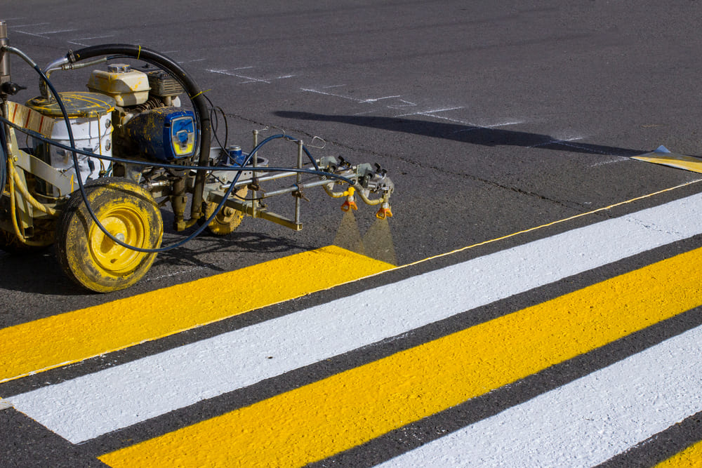 a machine marking a paint in the road as yelllow and white colour